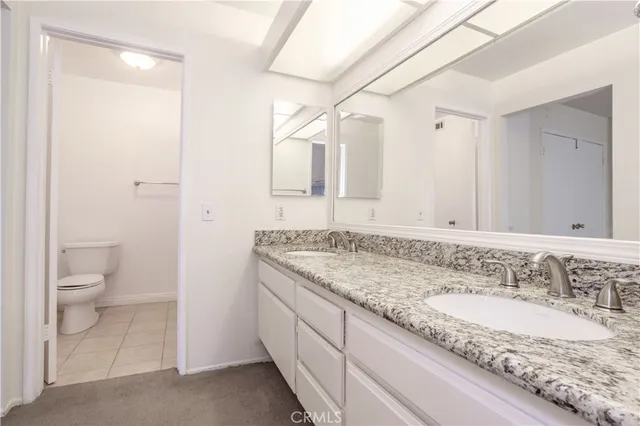 a bathroom with a granite countertop sink a toilet and a large mirror