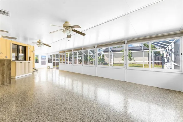 a view of an empty room with wooden floor and a ceiling fan