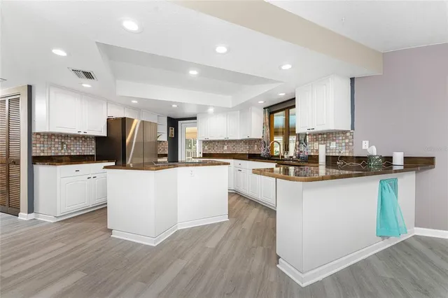 a kitchen with stainless steel appliances granite countertop a refrigerator a stove and a wooden floors