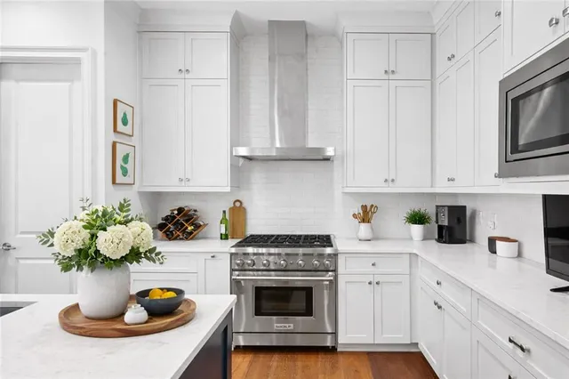 a kitchen with a stove a sink and white cabinets