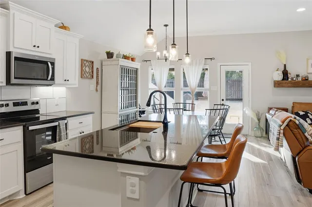 a kitchen with granite countertop a table chairs stove and microwave