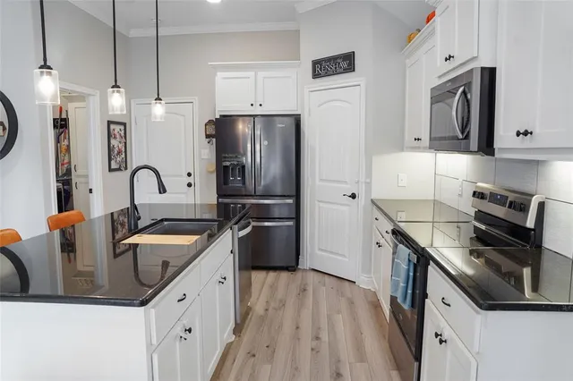 a kitchen with granite countertop a sink a counter space stainless steel appliances and cabinets