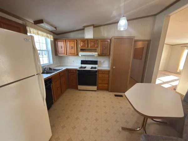 a kitchen with stainless steel appliances granite countertop a refrigerator a sink dishwasher a stove a washer dryer and a dining table with wooden cabinet