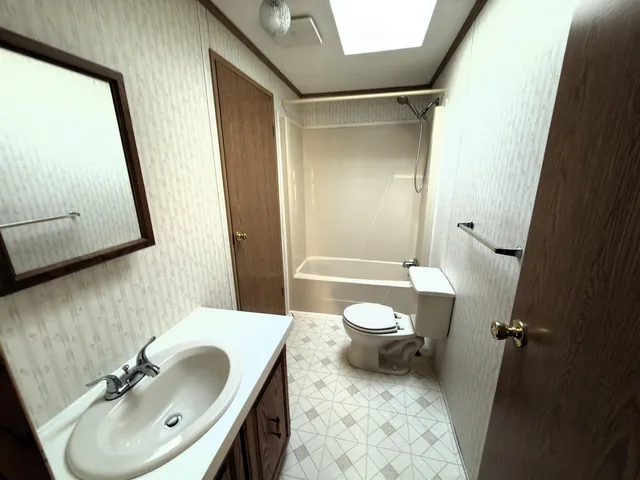 a bathroom with a sink a toilet a mirror and shower