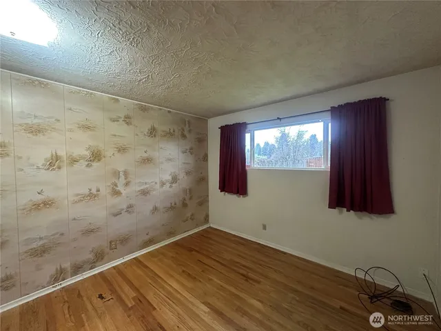 a view of empty room with window and wooden floor