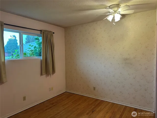 a view of empty room with wooden floor and fan