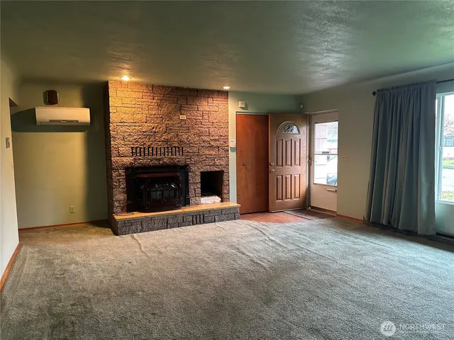 an empty room with windows and fireplace