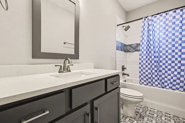 a bathroom with a granite countertop toilet sink and mirror