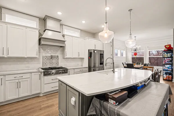 a large kitchen with stainless steel appliances kitchen island granite countertop a stove a sink a refrigerator and a white cabinets