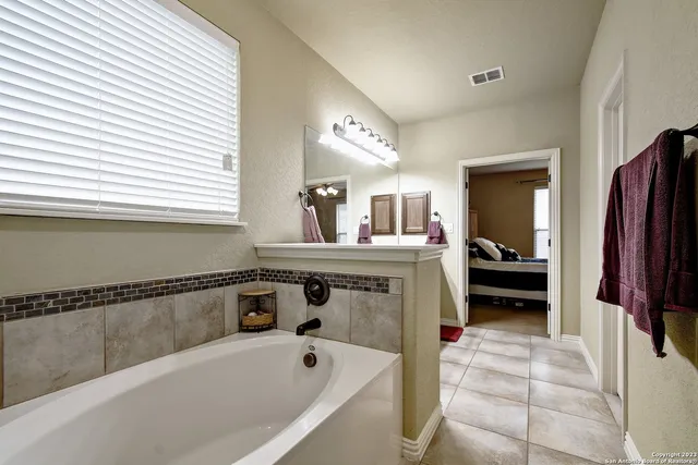 a en suite bathroom with a tub sink and a mirror