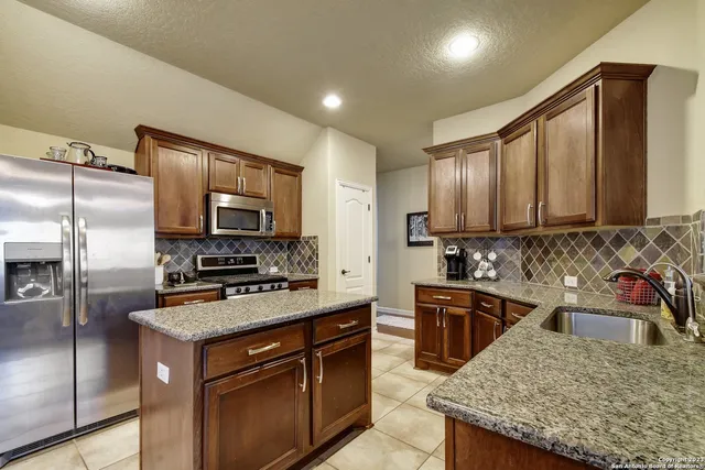 a kitchen with stainless steel appliances granite countertop a sink stove microwave and refrigerator
