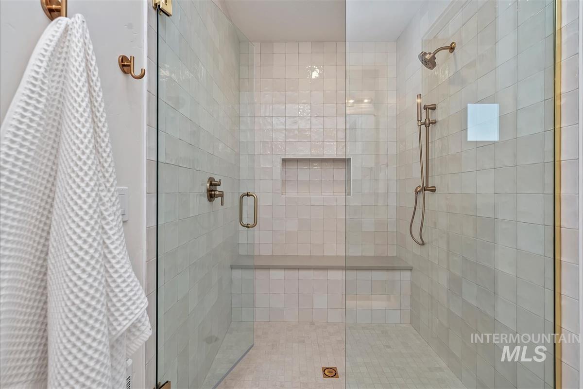 3219 West Moore Street Boise, ID 83702 - Photo 25 of 36 Walk-in shower featuring clear glass enclosure with bronze hardware, tiled walls, built-in bench, recessed shelf, and bronze shower fixtures including a handheld showerhead
