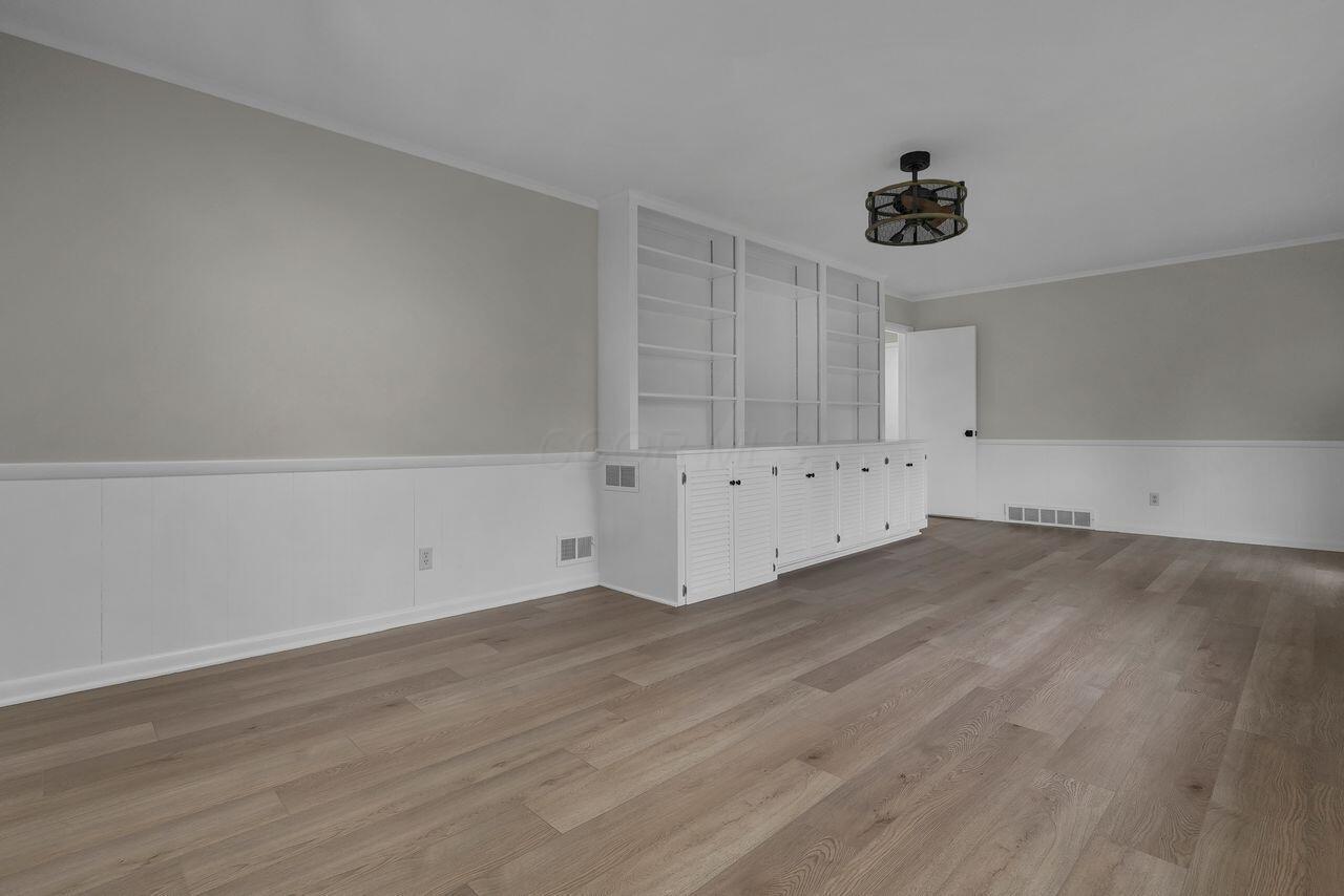 1535 Kenwick Road Columbus, OH 43209 - Photo 7 of 26 Family room wall with built-in shelving and cabinets, updated flooring, and neutral paint.