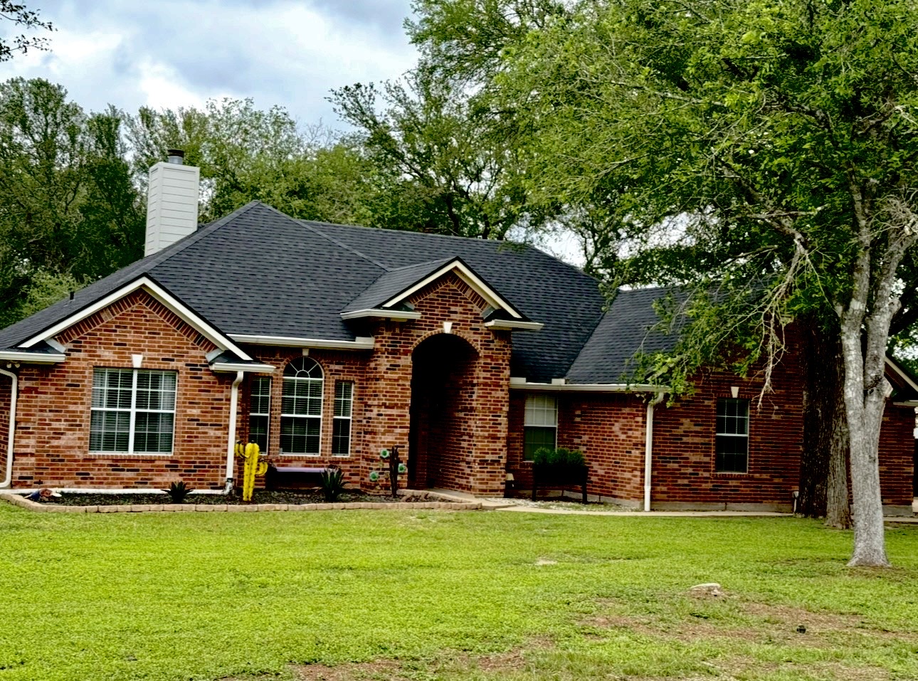 104 Spring Branch Bastrop, TX 78602 - Photo 2 of 32 Brick exterior featuring a gabled roofline, arched entry, and white-framed windows