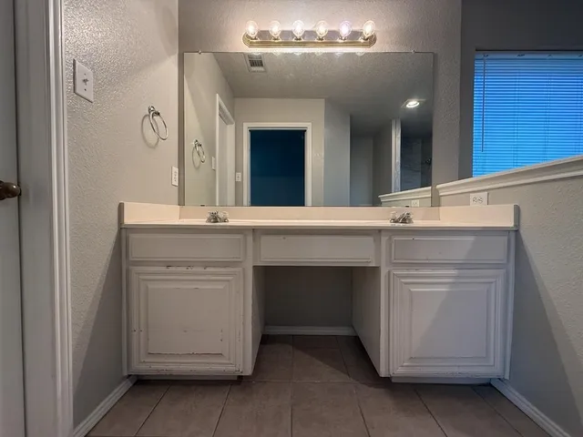 an empty room with a chandelier fan and windows