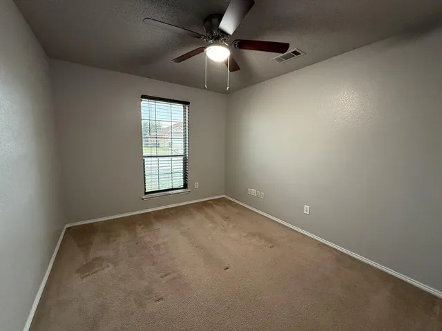 an empty room with a ceiling fan and window