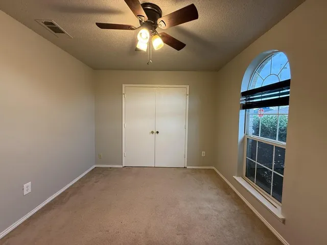 an empty room with a window and a fan