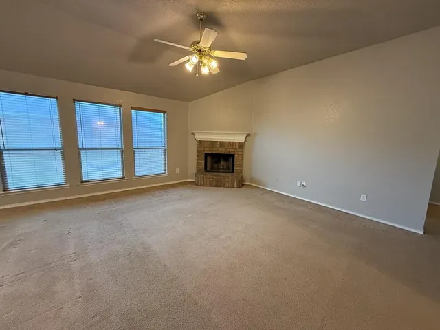 a view of an empty room with a fireplace and a window