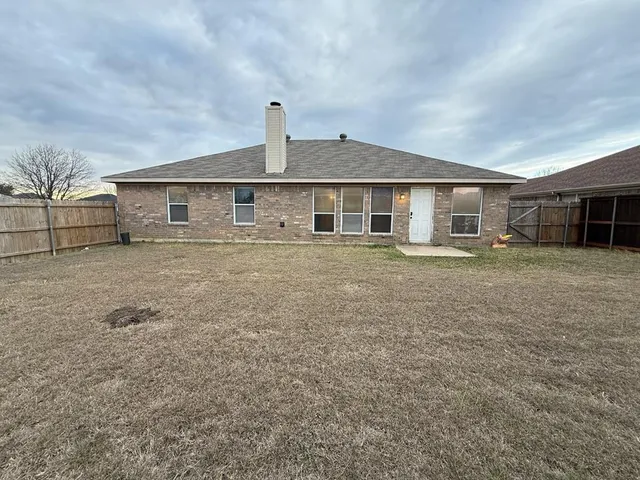a view of a yard in front of a house with wooden fence