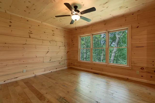a view of an empty room with wooden floor and a fireplace