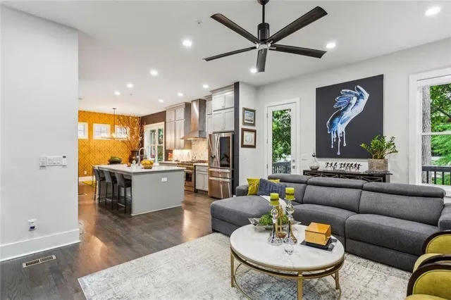 a living room with stainless steel appliances kitchen island granite countertop furniture and a wooden floor