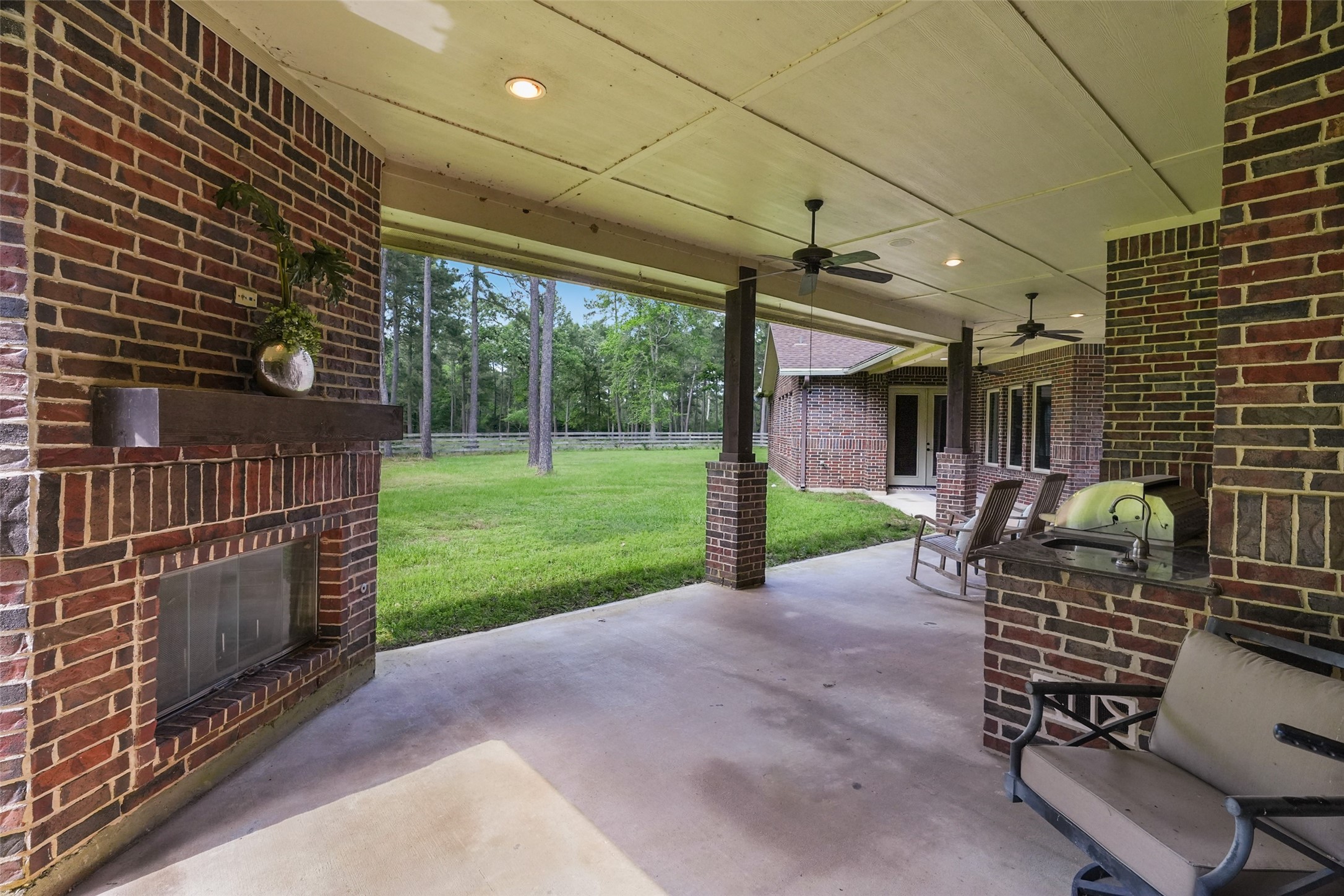 26250 A Riley Road Waller, TX 77484 - Photo 24 of 50 Covered outdoor kitchen and living area with built-in grill, sink, and fireplace—perfect for year-round cookouts.