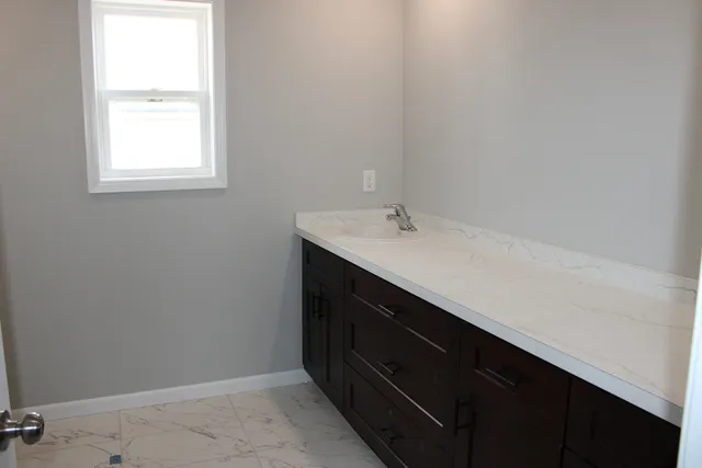 a bathroom with a sink vanity and a window
