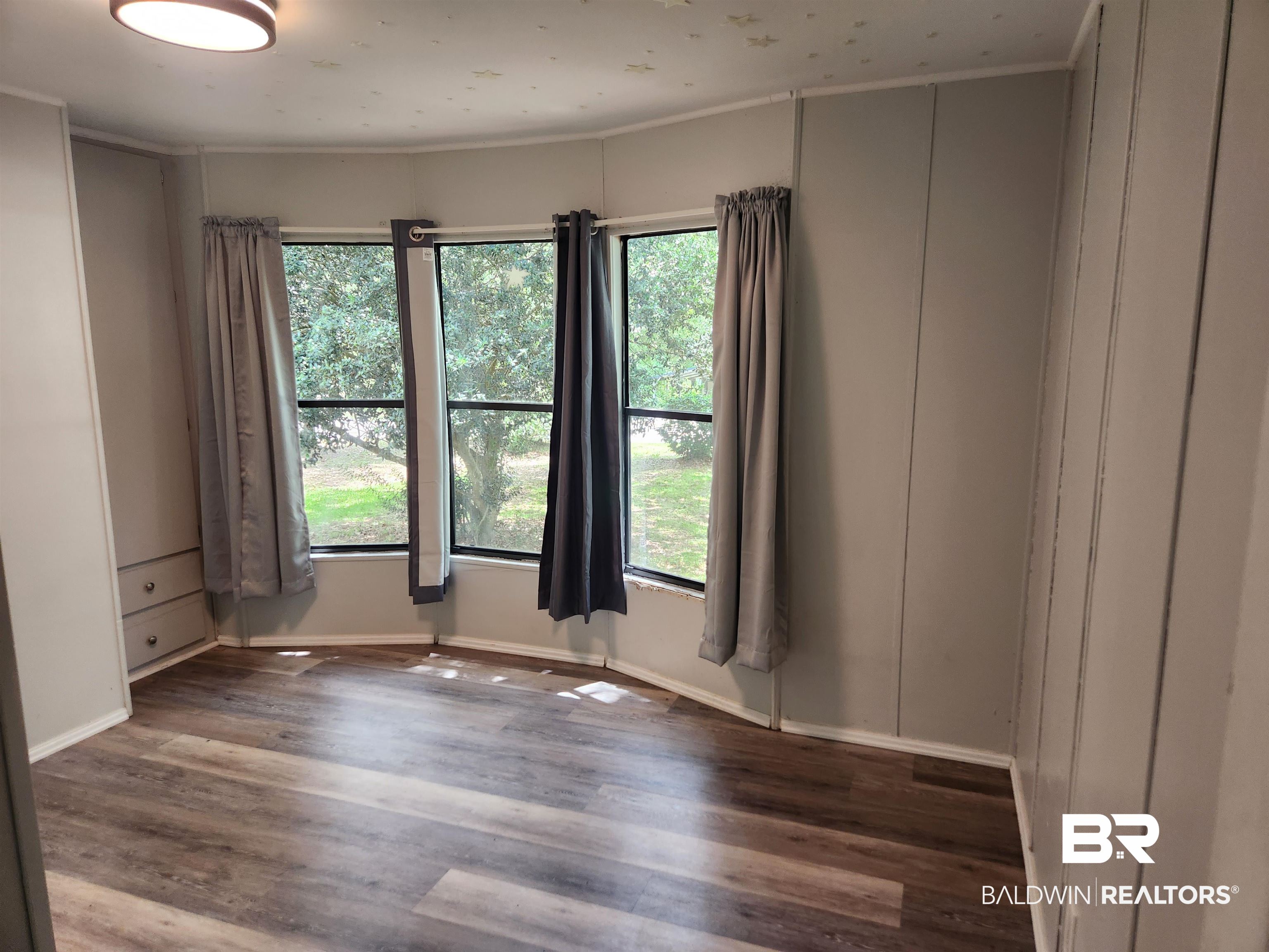 23051 Fritz Lane Foley, AL 36535 - Photo 12 of 26 Bay window with exterior views, wood-finish flooring, built-in cabinetry, and neutral wall panels