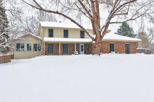 a front view of a house with a yard covered in snow