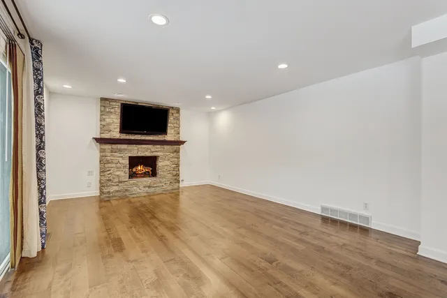 a view of empty room with wooden floor and fireplace