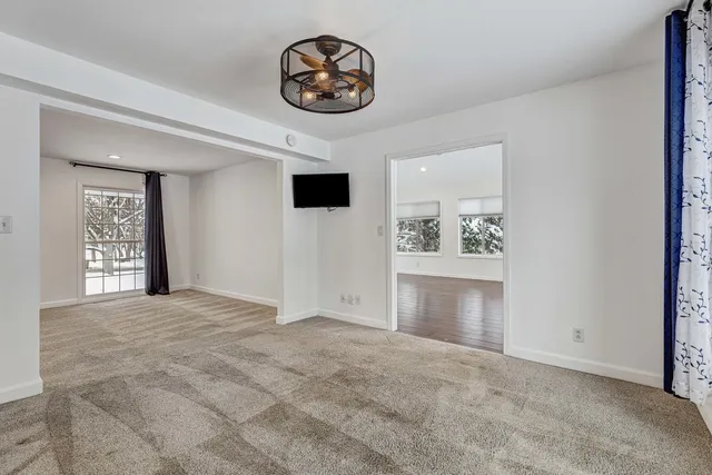 a view of an empty room with a window and kitchen view