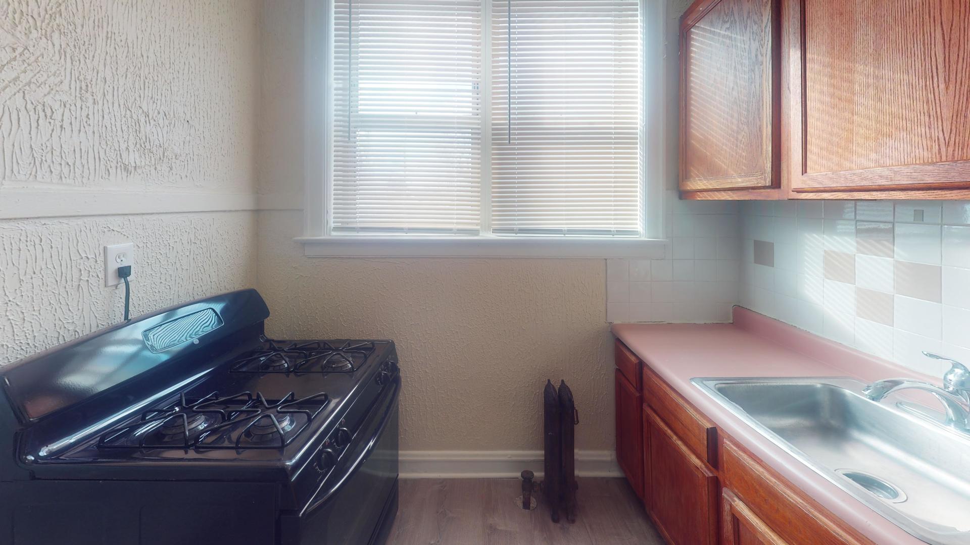 621 East 89th Place, Unit 1N Chicago, IL 60619 - Photo 7 of 8 a kitchen with granite countertop a stove and a sink