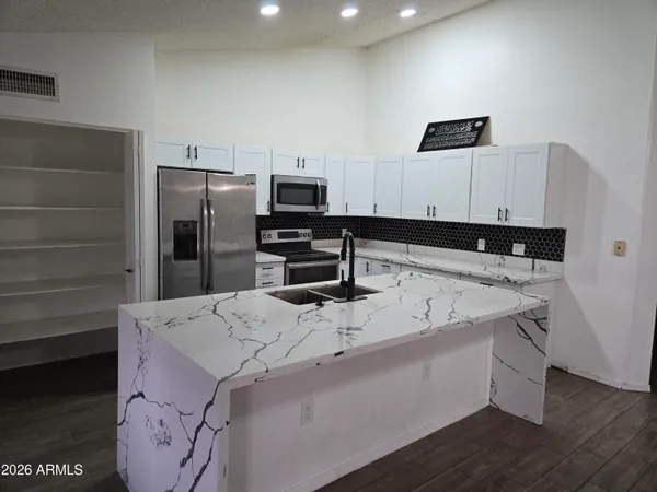 a kitchen with kitchen island white cabinets and stainless steel appliances