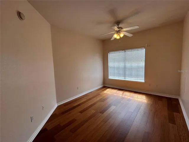 a view of empty room with wooden floor and fan