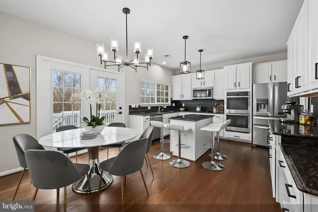 a kitchen with stainless steel appliances white cabinets a sink a stove a refrigerator and white cabinets