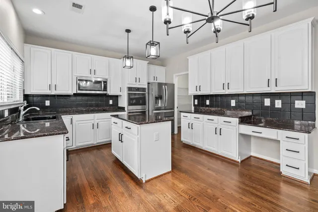 a kitchen with stainless steel appliances granite countertop a sink a stove and a wooden floors