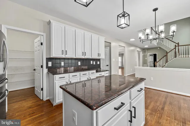 a kitchen with stainless steel appliances granite countertop a stove and a refrigerator with white cabinets