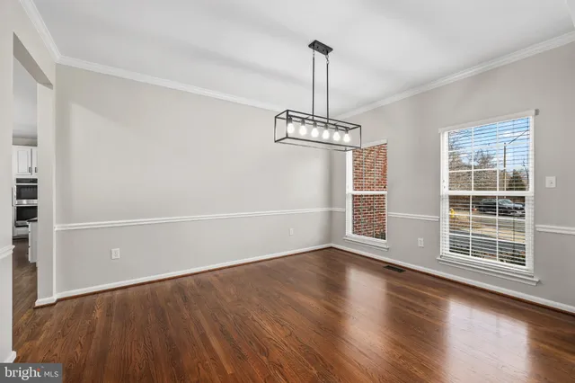 a view of empty room with wooden floor fan and window