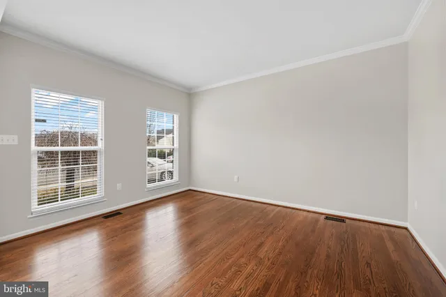 a view of an empty room with wooden floor and windows