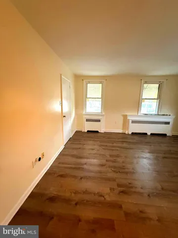 a view of a hallway to a livingroom with wooden floor and furniture