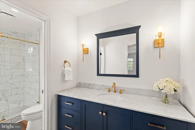 a bathroom with a granite countertop sink a toilet and a mirror