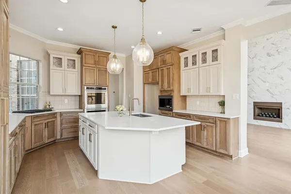 a large kitchen with stainless steel appliances granite countertop a stove top oven a sink a dishwasher and a dining table with wooden floor