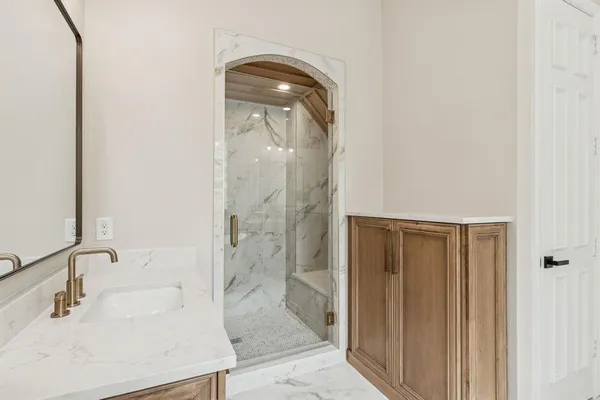 a bathroom with a sink a glass door shower and a mirror
