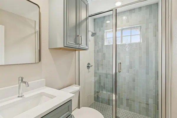 a bathroom with a shower sink vanity and mirror