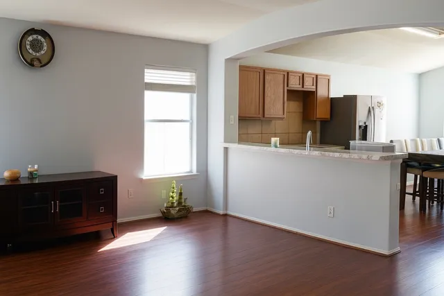 a living room with stainless steel appliances kitchen island granite countertop a sink a window and wooden floor