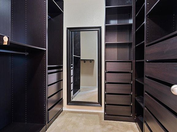 904 Lonesome Lilly Way Pflugerville, TX 78660 - Photo 22 of 34 The property features a spacious walk-in closet with dark wood shelving, integrated drawers, and a full-length mirror