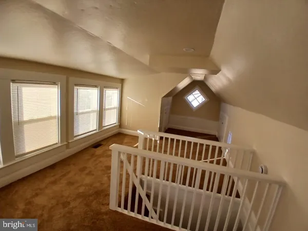 a view of an empty room with wooden floor and windows