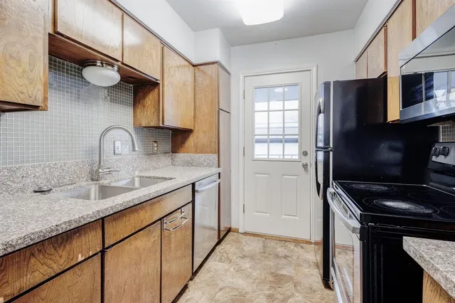 a kitchen with stainless steel appliances a sink cabinets and a window