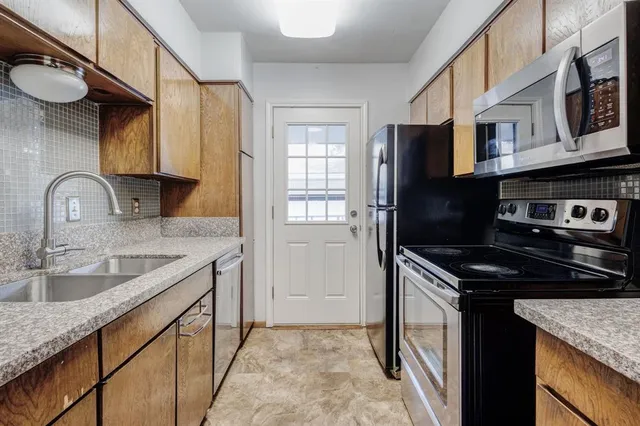 a kitchen with granite countertop a stove sink and refrigerator