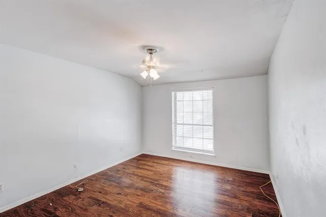 an empty room with wooden floor and window